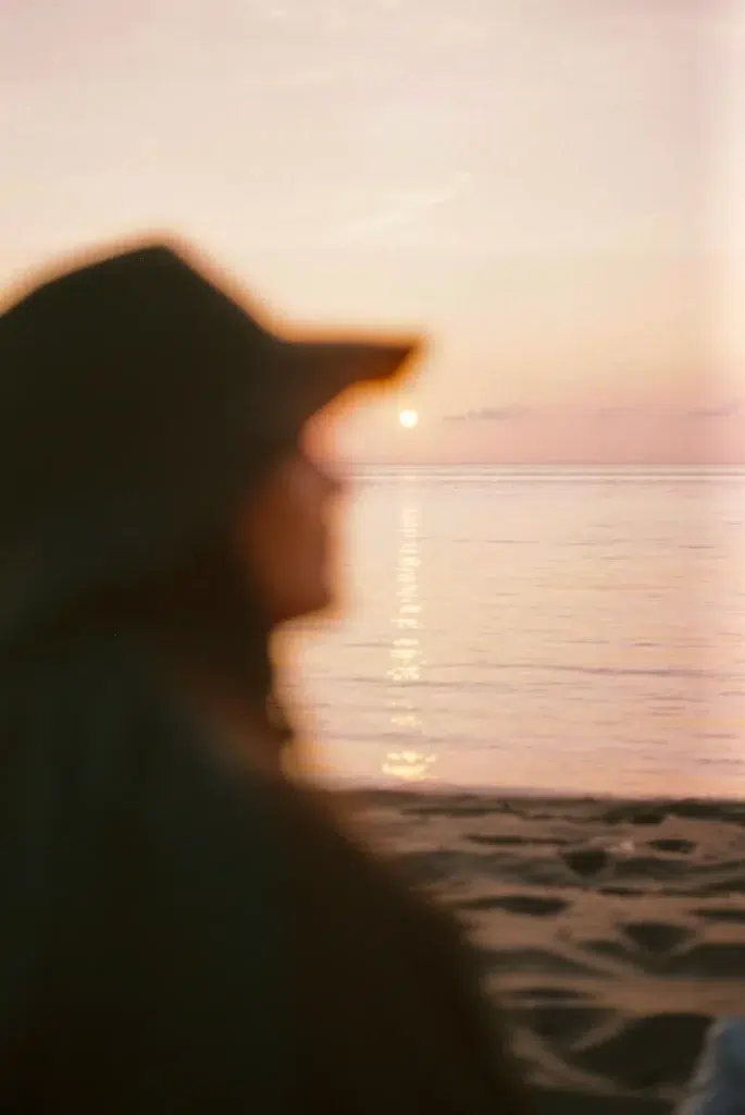 Portrait flouté d’une femme face à la mer au coucher du soleil